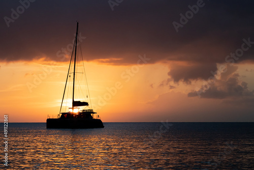 Silhouette of a sail boat sailing off into the of sunset on the distant ocean horizon
