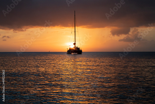 Sailboat sailing off into the sunset on the ocean horizon