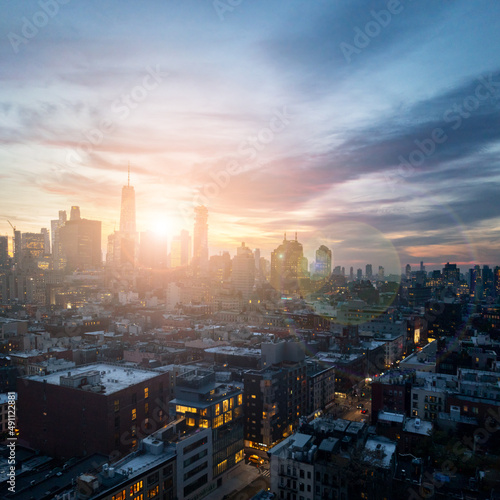 New York City skyline at dusk with sunlight shining behind the buildings of Lower Manhattan