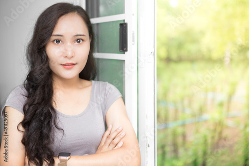 Free Download Beautiful Asian business woman wearing grey casual shirt relaxing at the window and admiring nature and copy space.  Confident Asian working woman smiling and cheerful - GFXLoad