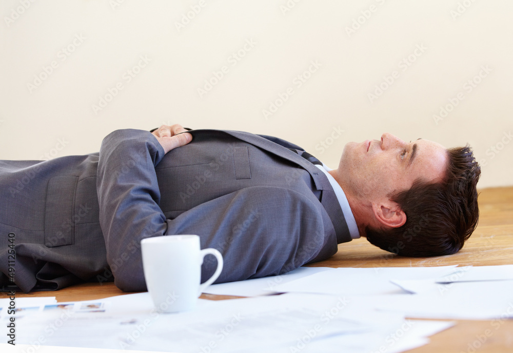 Work really takes its toll. A handsome young businessman lying on the floor of his office. Work really takes its toll. A handsome young businessman lying on the floor of his office.