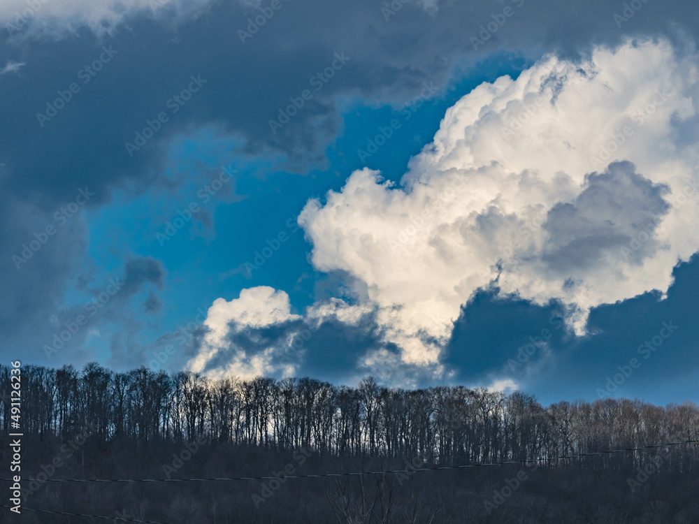 Dramatic sky and clouds with forest ridge mountain in the foreground, day light with silhouetted trees. Dramatic sky and clouds with forest ridge mountain in the foreground, day light with silhouetted trees.