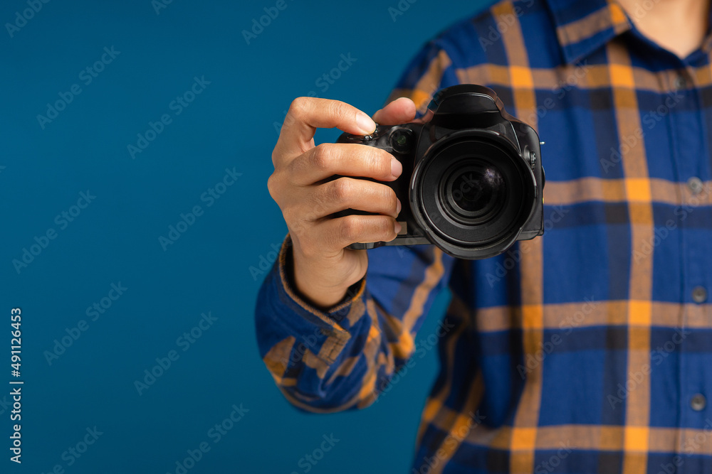 Close-up of hand holding the digital camera while standing on a blue background Close-up of hand holding the digital camera while standing on a blue background