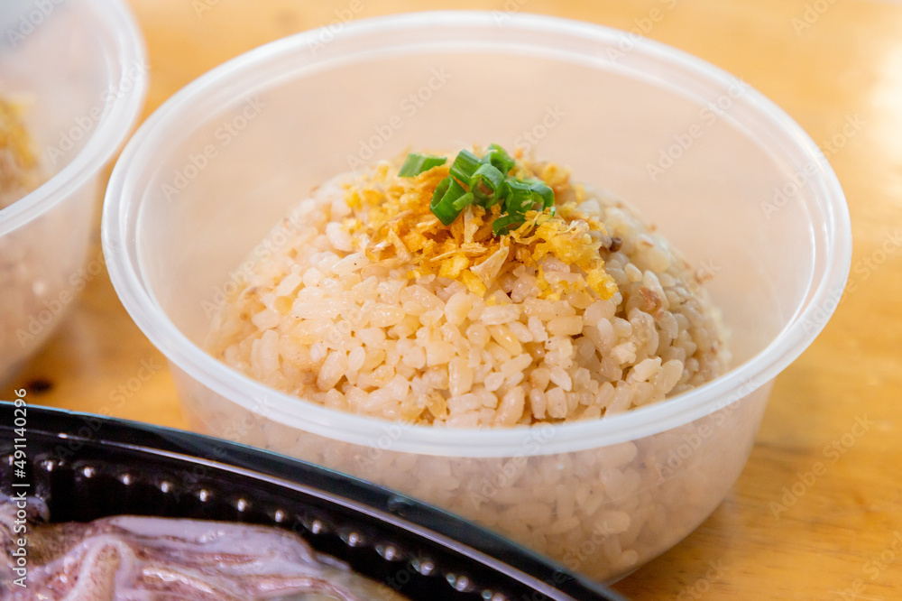Garlic fried rice in transparent plastic, on a wooden table.
Garlic fried rice in transparent plastic, on a wooden table.