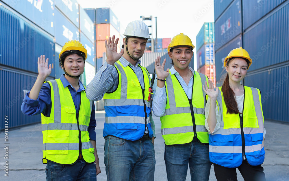 Group of multiethnic technician engineer or worker in protective uniform with hardhat standing and give high five celebrate successful together or completed deal commitment at container cargo site Group of multiethnic technician engineer or worker in protective uniform with hardhat standing and give high five celebrate successful together or completed deal commitment at container cargo site