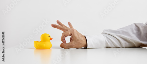 Job dismissal, unemployment or being fired from a work. Businessman hand is about to flick the rubber duckling. photo