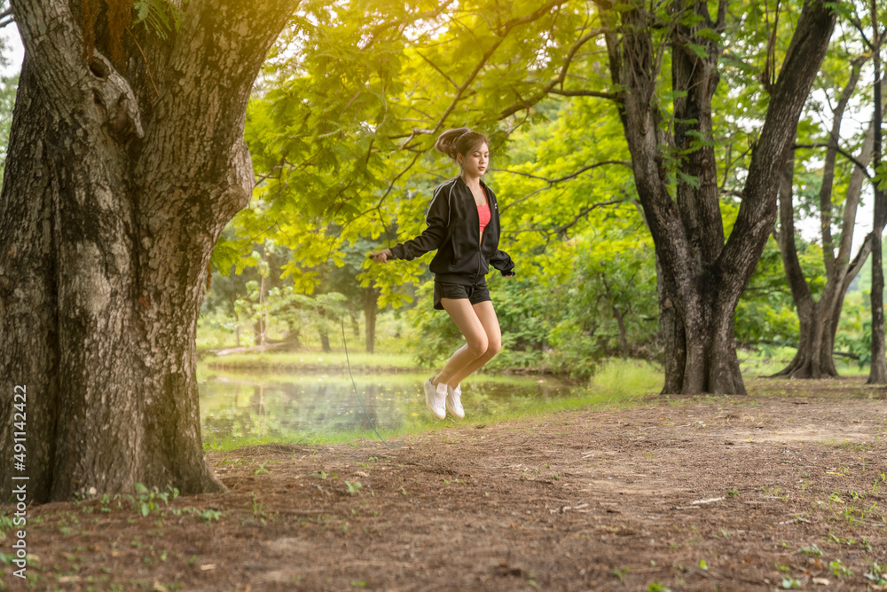 Outdoor shot  sporty woman working out with jump rope in a park on a sunny day.