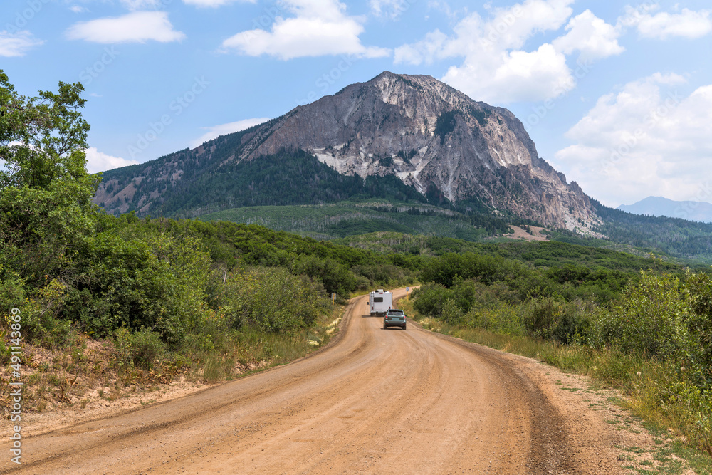 Fototapeta premium Kebler Pass - A Summer day view of Kebler Pass Road winding at base of Marcellina Mountain of Elk Mountains. Crested Butte, Colorado, USA.