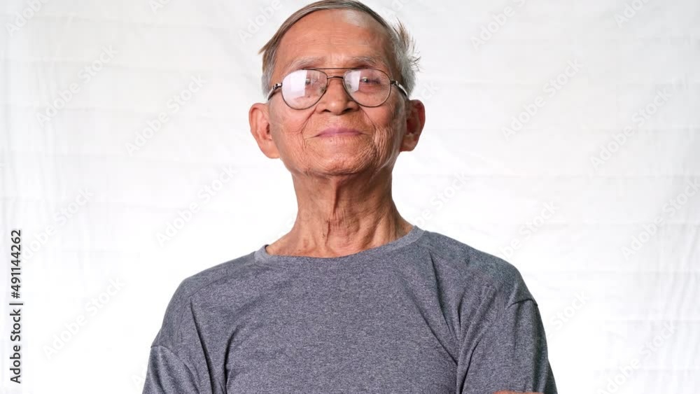 Asian senior man smiling happily at home. Cheerful old man enjoyed his retirement life and looked at the camera indoors. Asian senior man smiling happily at home. Cheerful old man enjoyed his retirement life and looked at the camera indoors.