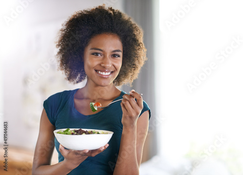 Getting her greens. Portrait of an attractive young woman eating a bowl of salad. photo