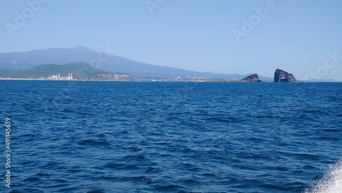 The calm blue sea and the small rock that you can see far away.