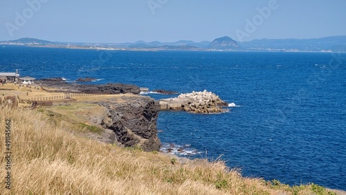 The golden hill, the blue sea, and the small breakwater.