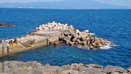 The small breakwater installed in the blue sea and people watching.