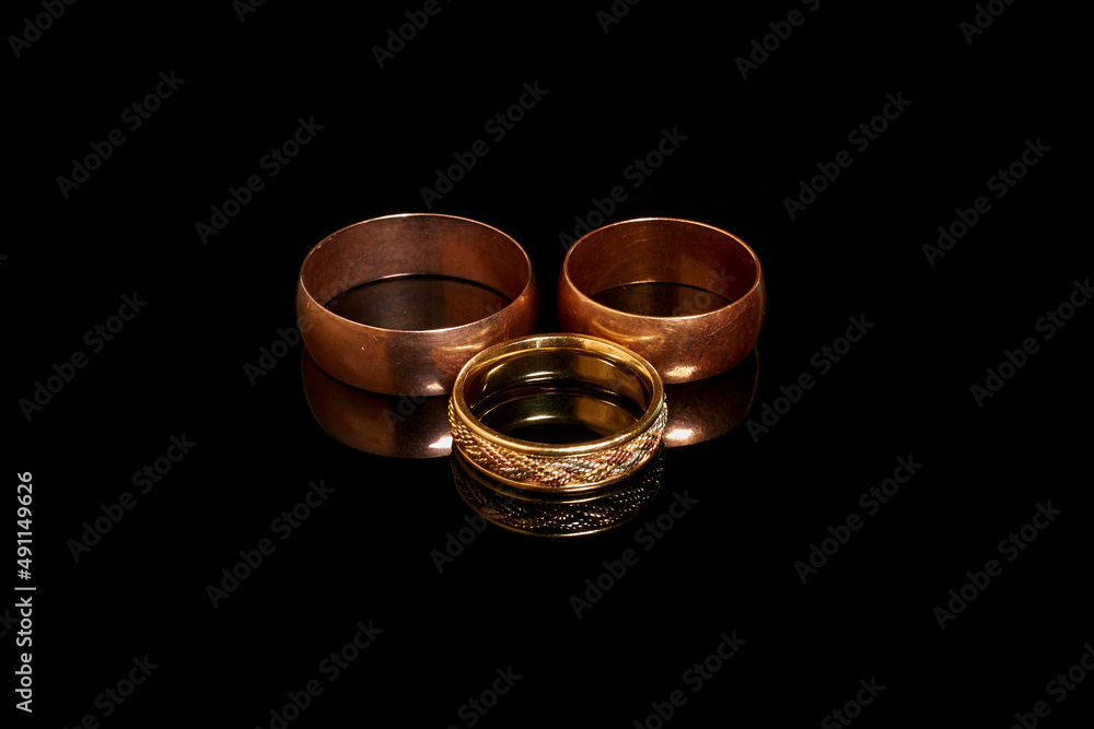 Three gold wedding rings on a black background Three gold wedding rings on a black background