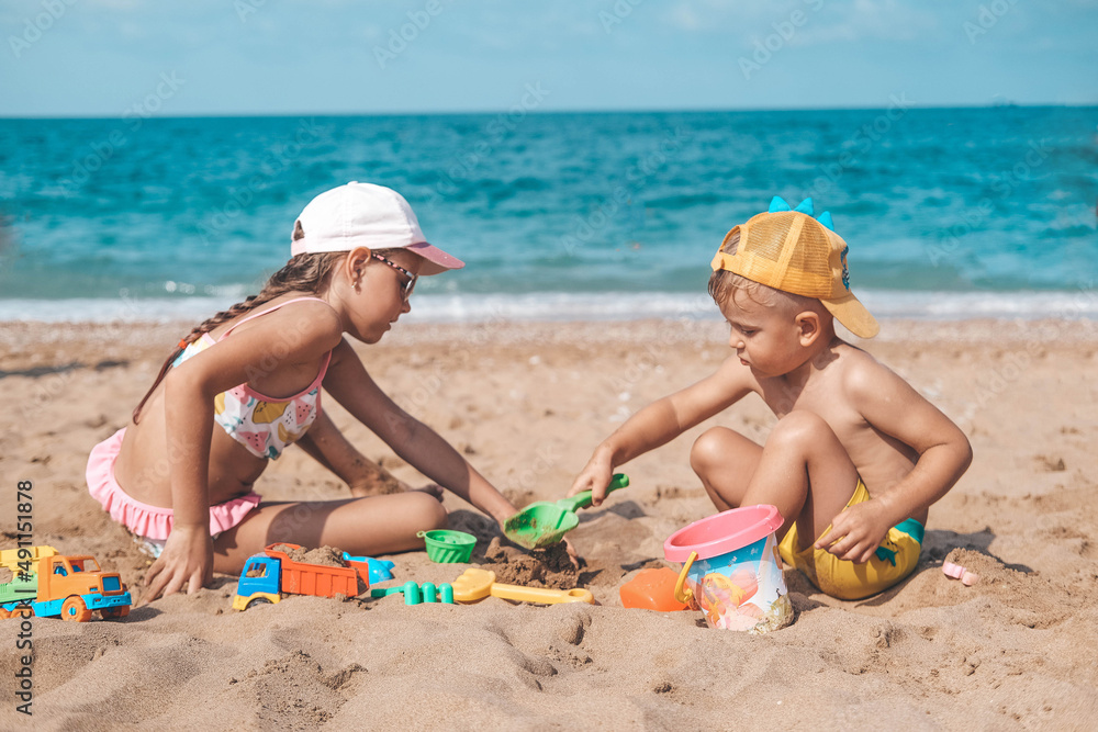 Children are playing on the beach. Summer water fun for the whole family. A boy and a girl are playing with sand on the seashore. Children are playing on the beach. Summer water fun for the whole family. A boy and a girl are playing with sand on the seashore.