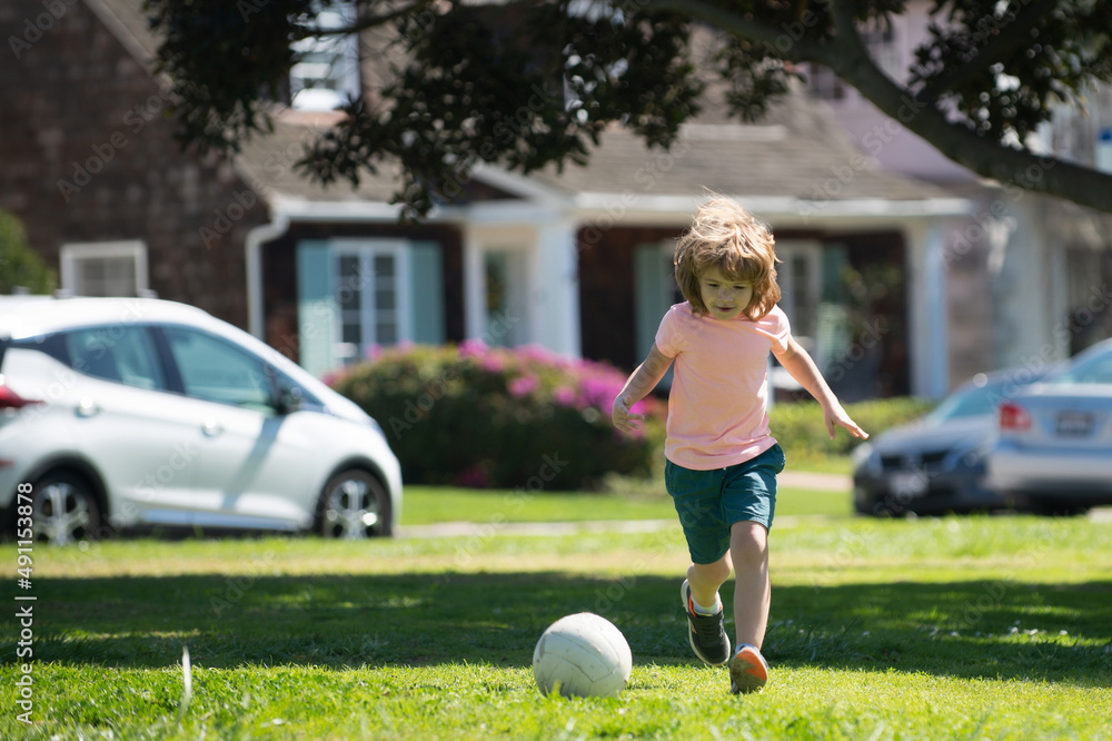 Excited child boy kicking ball in the grass outdoors. Soccer kids, children play football. Child soccer play football in park. Excited child boy kicking ball in the grass outdoors. Soccer kids, children play football. Child soccer play football in park.