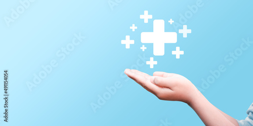 hand holding plus icon on blue background. Plus sign virtual means to offer positive thing (like benefits, personal development, social network)Profit,health insurance, growth concepts.