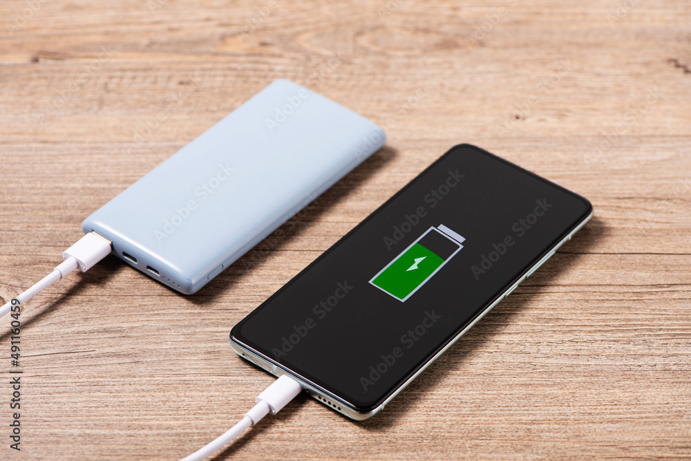 Smartphone Charging with a Power Bank Through Spiral USB Cable on table Smartphone Charging with a Power Bank Through Spiral USB Cable on table