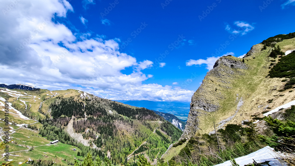 Mountain peak of Hahnkogel (Klek) with panoramic view in spring in the Karawanks, Carinthia, Austria. Borders Austria, Slovenia, Italy. Triglav National Park. Alpine meadows. Alm. Snow fields melting