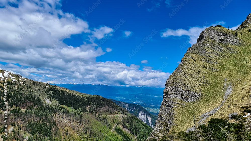 Mountain peak of Hahnkogel (Klek) with panoramic view in spring in the Karawanks, Carinthia, Austria. Borders Austria, Slovenia, Italy. Triglav National Park. Alpine meadows. Alm. Snow fields melting