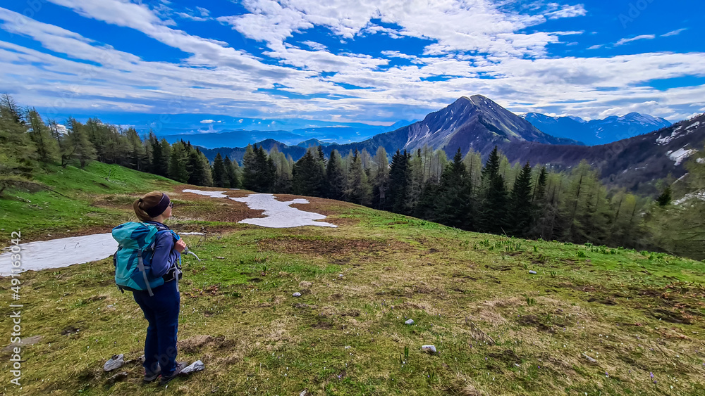 Woman admiring the scenic view near Frauenkogel on the mountain peaks in the Karawanks, Carinthia, Austria. Borders Austria, Slovenia, Italy. Triglav National Park. Looking on Kahlkogel (Golica).