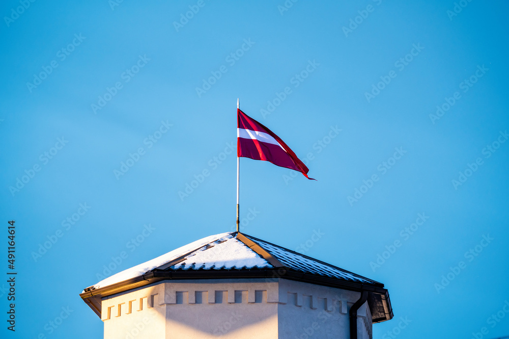 Latvian Flag on the flagpole fluttering in the wind against blue clear sky, copy space