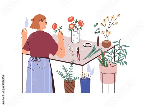 Florist with plants in vases, smelling flowers in floral shop. Woman works wi...