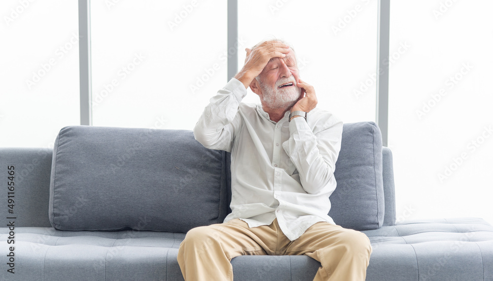 Elderly patients in sofa. Senior man patients headache hands on forehead. Man touching forehead suffering from severe headache or recalling bad memories. Medical and healthcare concept
