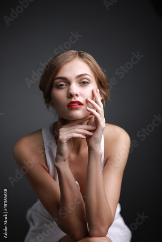 expressive studio portrait of a young attractive girl in a white dress