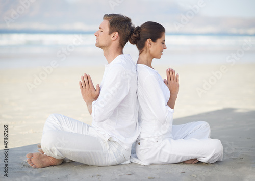 Seaside yoga. A young couple practising yoga on the beach.