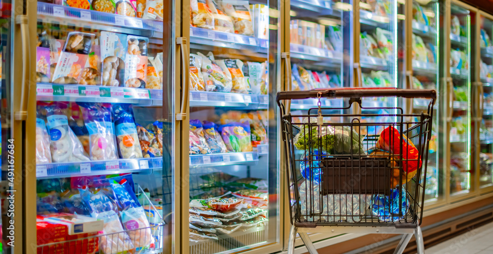 Fototapeta premium A shopping cart with grocery products in a supermarket