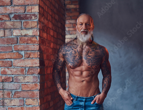 Muscular elderly man with tattooed body indoors room