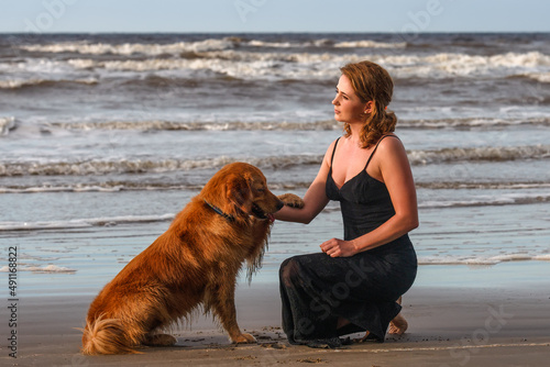 smiling young woman playing with her dog on the beach