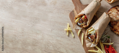 Gyro pita Shawarma wrap on wood table. Greek food with slice cut meat, overhead photo