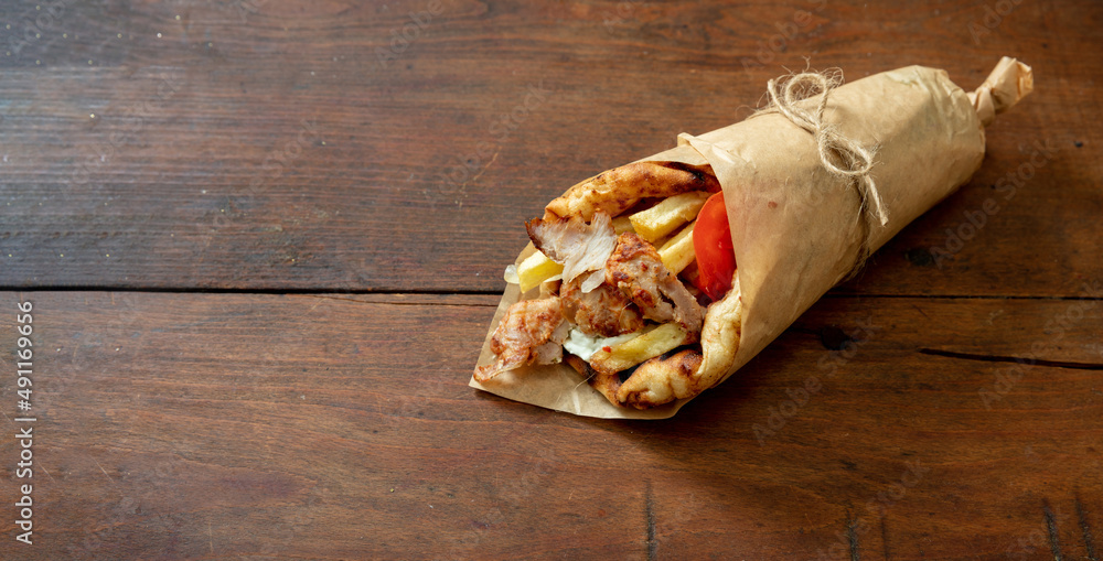 Gyro pita Shawarma wrap on wood table. Greek food with slice cut meat, overhead - obrazy, fototapety, plakaty 