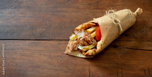 Gyro pita Shawarma wrap on wood table. Greek food with slice cut meat, overhead photo