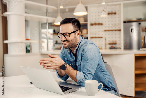 A man smiling at the laptop at his cozy home.