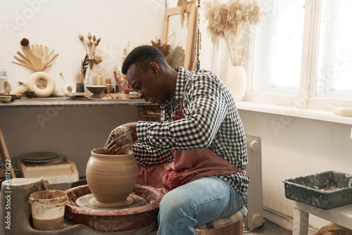 Cheerful man working on new clay vessel photo