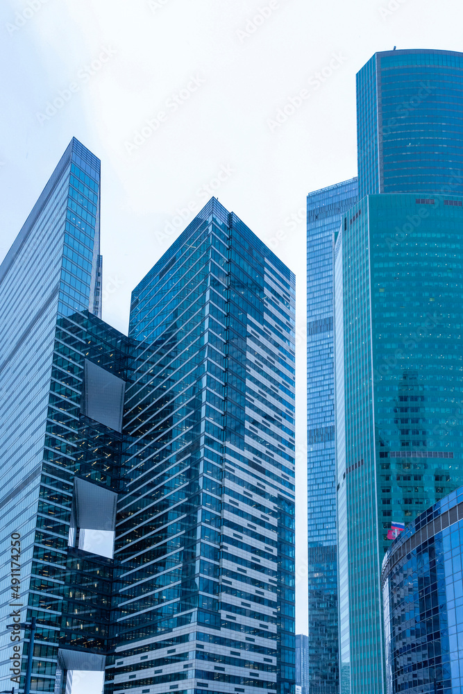 The tops of modern corporate buildings in snowfall. Low angle view of skyscrapers. The tops of modern corporate buildings in snowfall. Low angle view of skyscrapers.