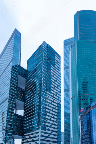The tops of modern corporate buildings in snowfall. Low angle view of skyscrapers.