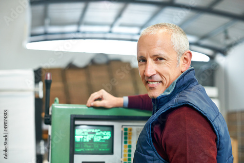 This panel is the nerve center of the factory. Portrait of a mature man standing next to machinery in a factory.