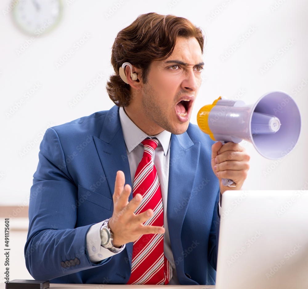 The deaf employee using hearing aid in office The deaf employee using hearing aid in office