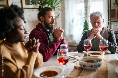 Family and religious concept. Group of multiethnic people with food praying before meal