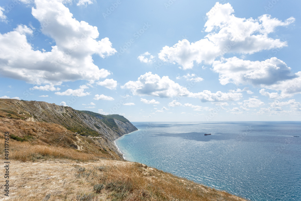 Beautiful landscape of high coast, blue sea and fluffy clouds on a sunny summer day. The Black Sea coast. Anapa