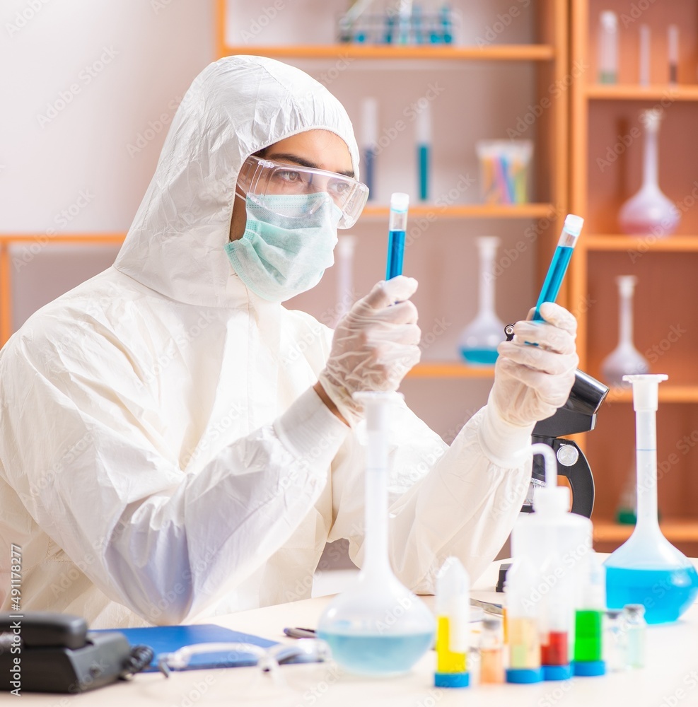 The young biochemist wearing protective suit working in the lab The young biochemist wearing protective suit working in the lab