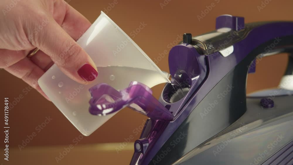 Closeup of a young woman filling laundry iron with distilled water