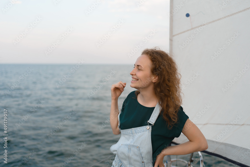 Smiling young red-haired woman on a yacht looking away in the middle of the sea Smiling young red-haired woman on a yacht looking away in the middle of the sea