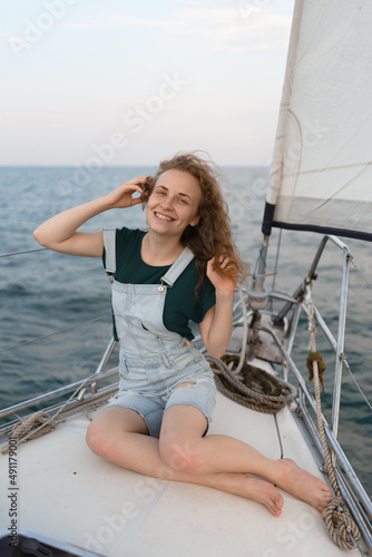 An attractive young woman is sitting on a yacht and enjoying a trip by the sea