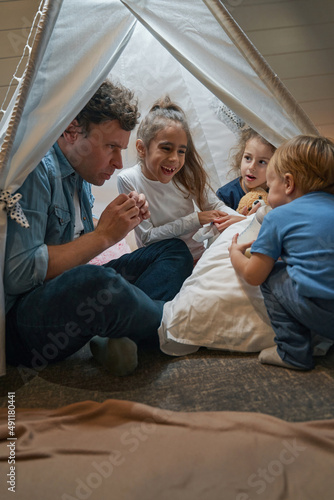 Smiling girls and brother spending time together with father