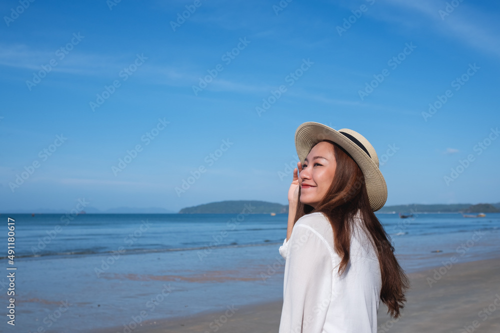 Portrait image of a beautiful young asian woman close her eyes while strolling on the beach with the sea and blue sky background Portrait image of a beautiful young asian woman close her eyes while strolling on the beach with the sea and blue sky background